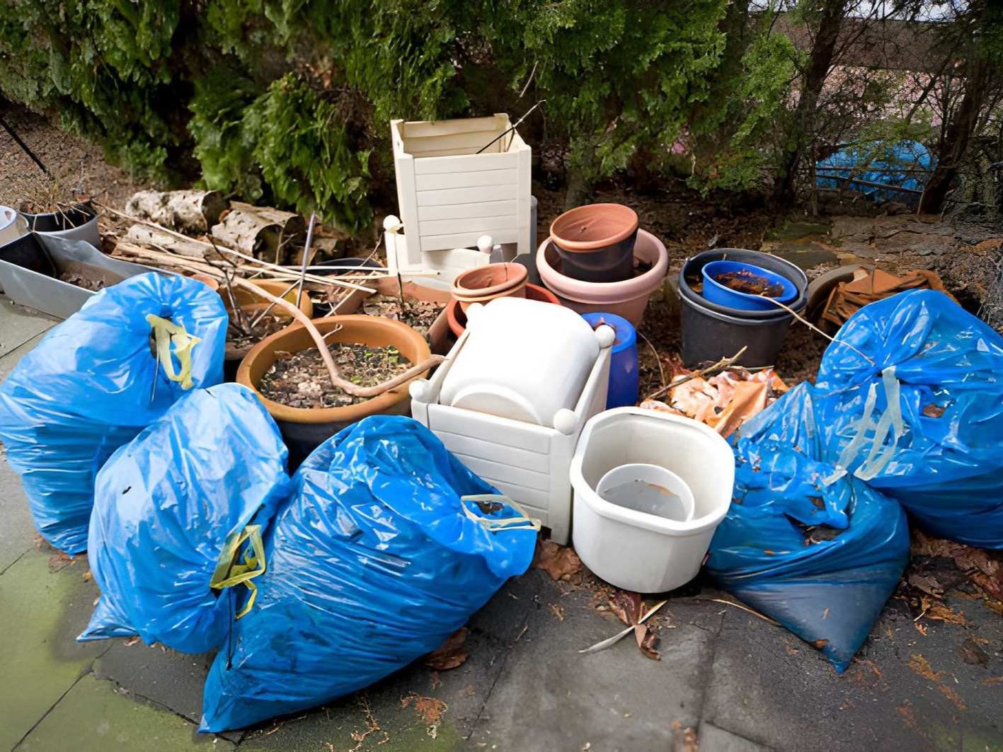 Pile of trash bags and various household items on the ground
